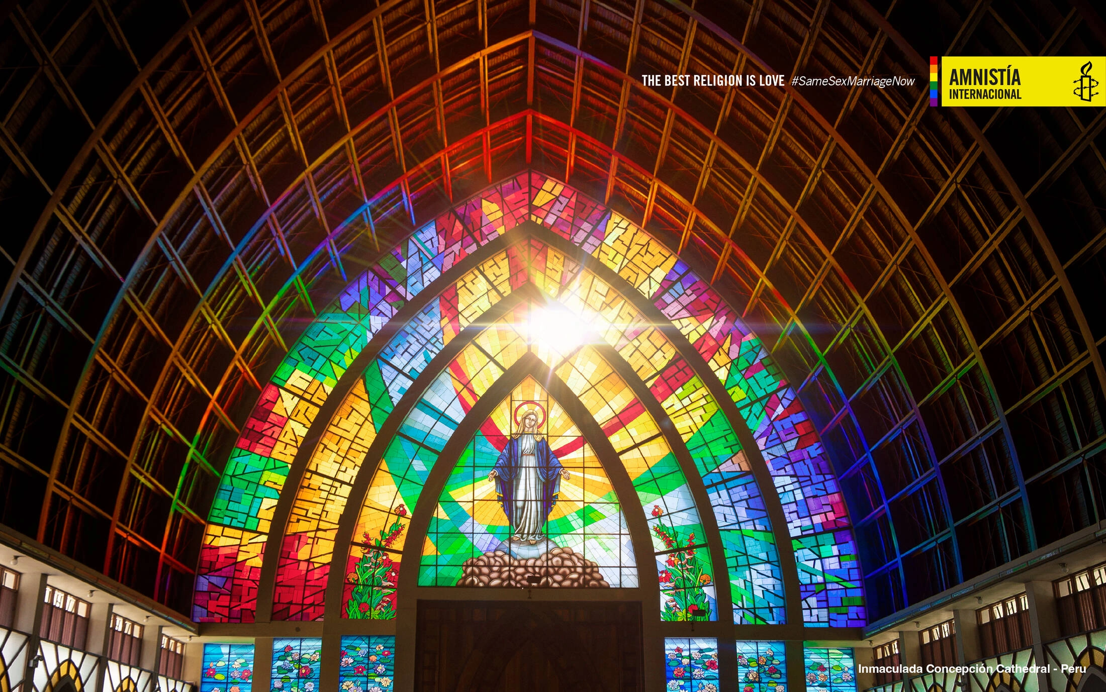 Vitral parabólico de un templo atravesado por la luz con los colores del orgullo