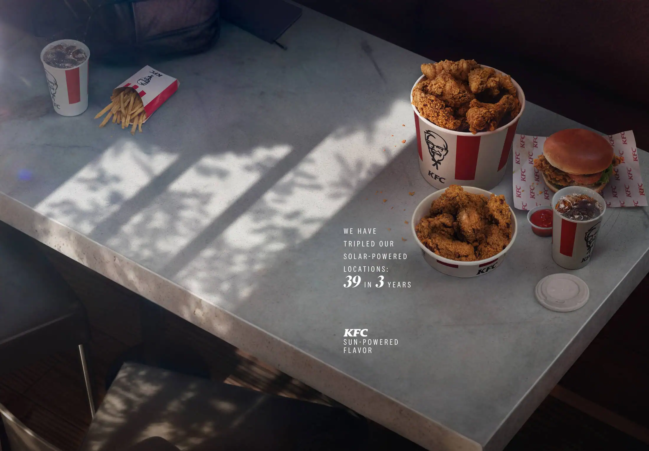 Pieza de Sun Stats de KFC: la luz del sol forma un gráfico de barras sobre una mesa cuadrada con comida